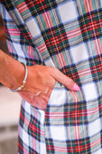 A hand with pink nail polish resting in the pocket of the cassidy dress in white christmas plaid pattern