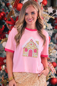 Pink short-sleeved tee featuring a foil gingerbread house appliqué with gold white details and pink trim on neckline and sleeves