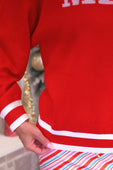 Red merry jacquard knit sweater in a varsity style with white ribbed cuffs and waistband featuring bold chest lettering