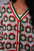 Festive white red and green ribbon wreath knit cardigan with a repeating wreath knit pattern and red bows